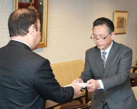 目録を手渡す高橋明夫代表理事組合長(奥)=山日YBS本社